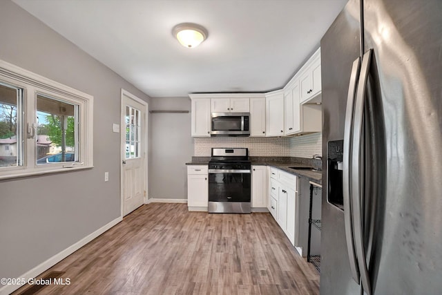 286 State Hwy Unit 80, Fort Plain, NY 13339 - kitchen featuring appliances with stainless steel finishes, dark countertops, decorative backsplash, light wood-style flooring, and white cabinets