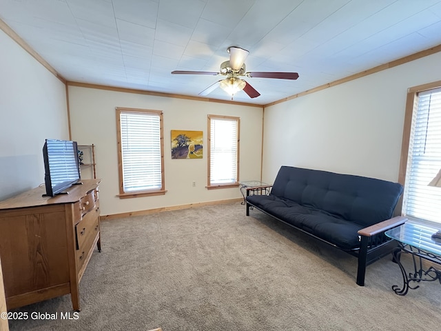 living area with baseboards, ornamental molding, carpet, and ceiling fan