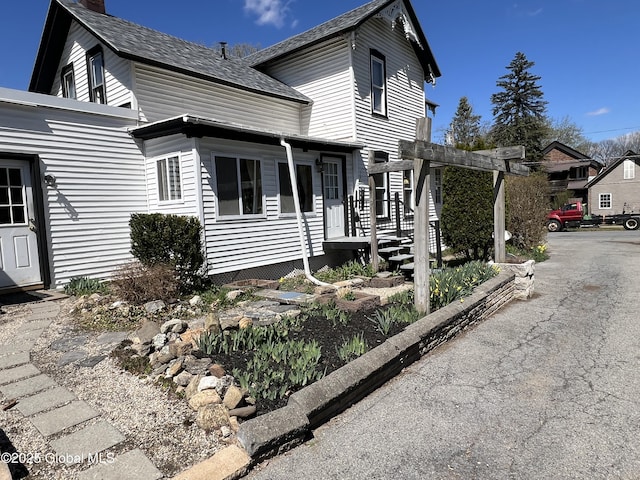 traditional home featuring a chimney and roof with shingles