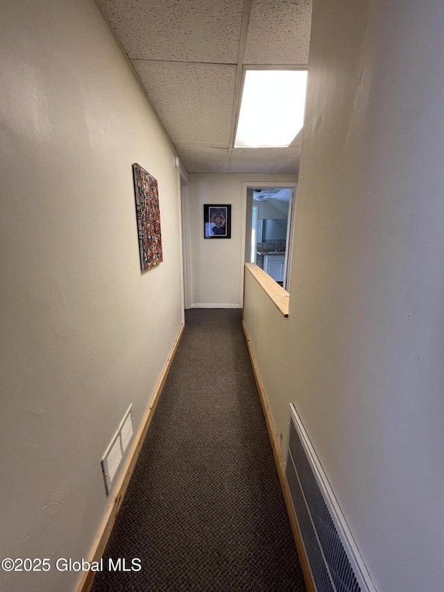 corridor with visible vents, carpet flooring, baseboards, and a drop ceiling
