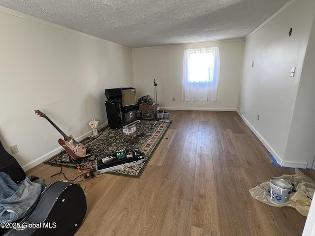 living area featuring baseboards, crown molding, wood finished floors, and a textured ceiling