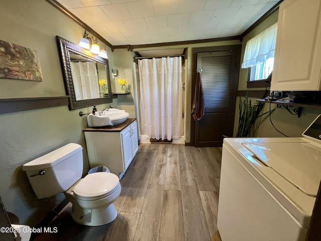 full bath with wood finished floors, vanity, washer / clothes dryer, toilet, and ornamental molding