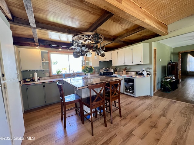 kitchen with wooden ceiling, a healthy amount of sunlight, beamed ceiling, and light wood finished floors