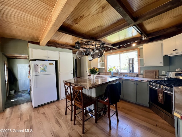 kitchen with open shelves, freestanding refrigerator, light wood-type flooring, gas stove, and wood ceiling