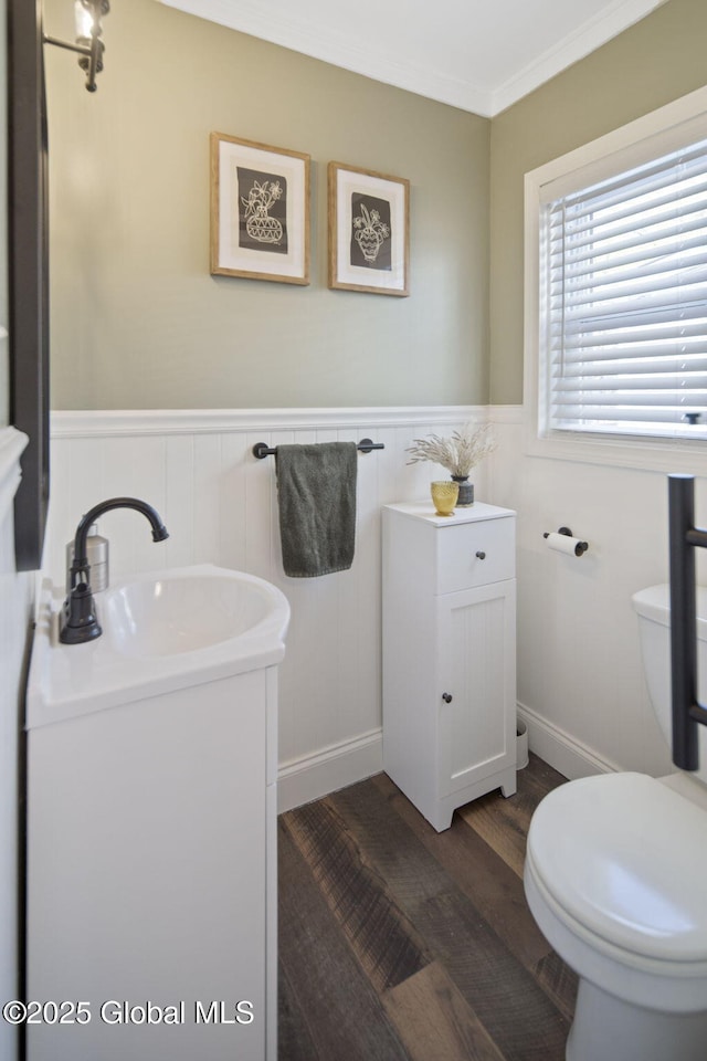 bathroom featuring crown molding, wood finished floors, vanity, a wainscoted wall, and toilet