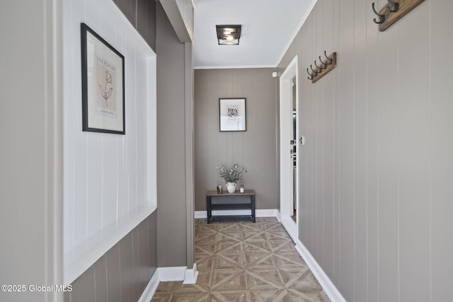 doorway to outside with baseboards, wood walls, and crown molding