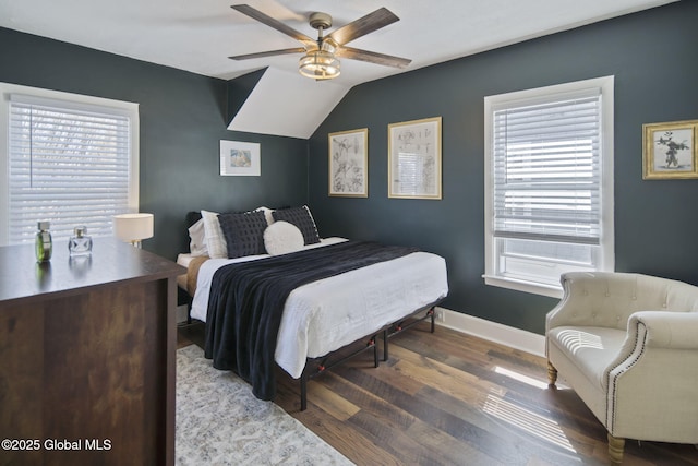 bedroom with baseboards, wood finished floors, vaulted ceiling, and multiple windows