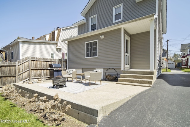 rear view of house with a patio area, an outdoor fire pit, and fence
