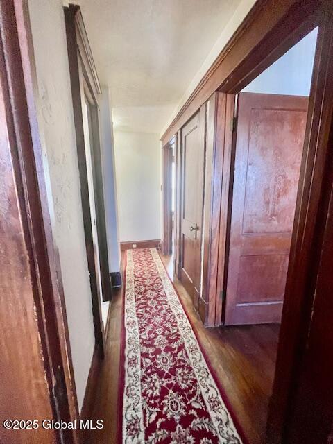 hall with baseboards and wood finished floors