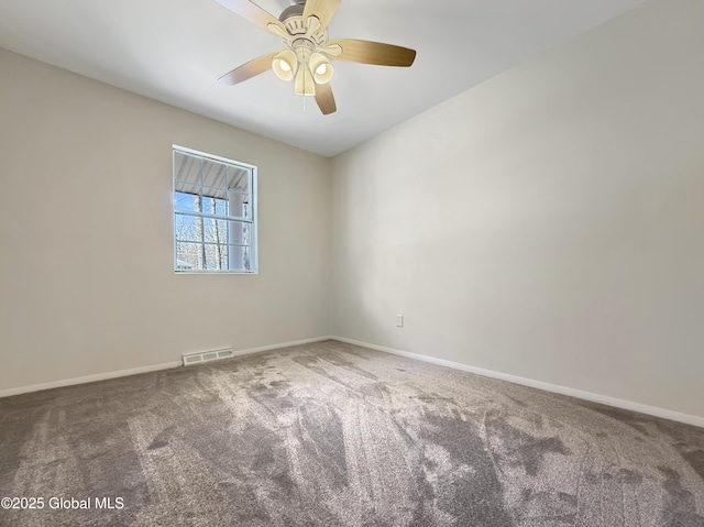 carpeted spare room with visible vents, baseboards, and ceiling fan