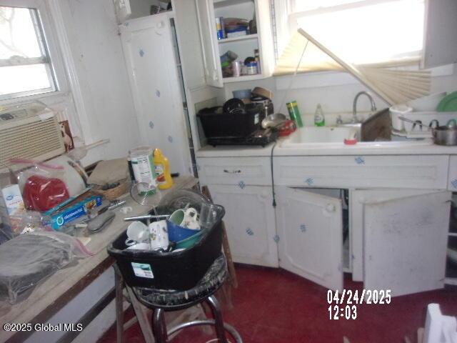 kitchen featuring white cabinetry, a sink, cooling unit, and light countertops