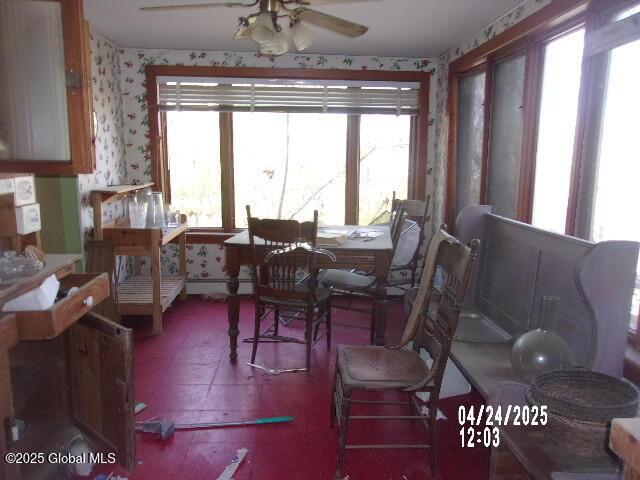 dining room with a baseboard radiator, wallpapered walls, a healthy amount of sunlight, and a ceiling fan