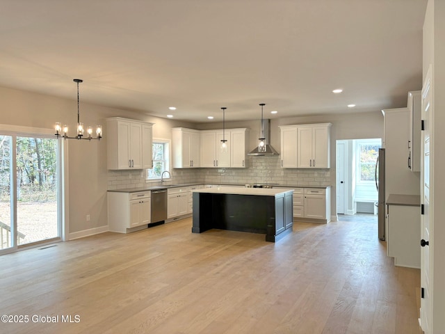kitchen featuring plenty of natural light, wall chimney exhaust hood, a sink, appliances with stainless steel finishes, and backsplash