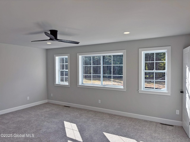 carpeted spare room featuring ceiling fan, visible vents, and baseboards