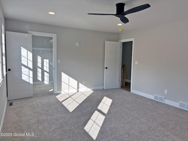 empty room with carpet floors, a ceiling fan, and visible vents