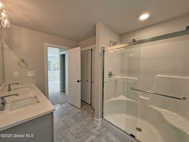 full bathroom with double vanity, baseboards, a sink, and a stall shower