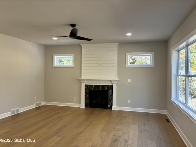 unfurnished living room featuring a healthy amount of sunlight, ceiling fan, and visible vents