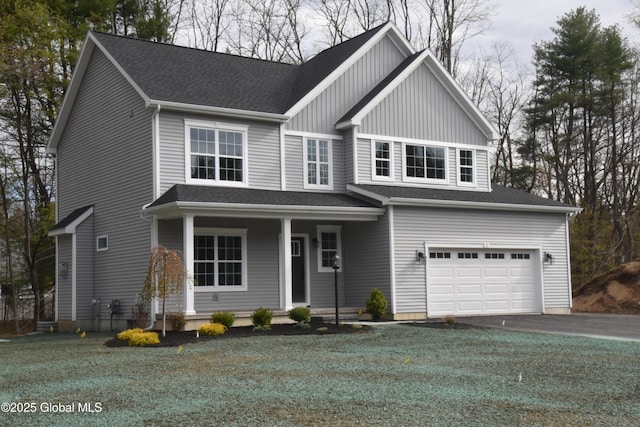 view of front of home with a garage, a front yard, covered porch, and driveway