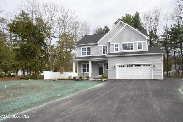 traditional-style house featuring fence, an attached garage, aphalt driveway, board and batten siding, and a porch