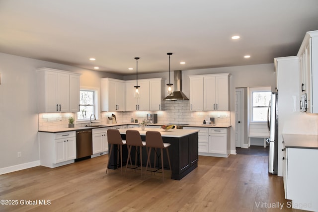 kitchen featuring a sink, white cabinetry, wall chimney range hood, and stainless steel appliances