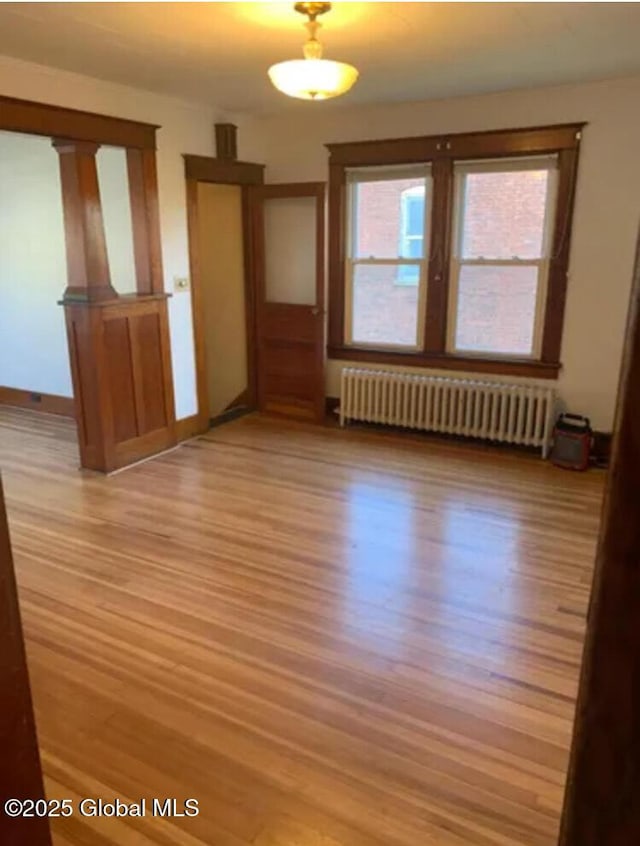 unfurnished room featuring radiator heating unit and light wood-type flooring