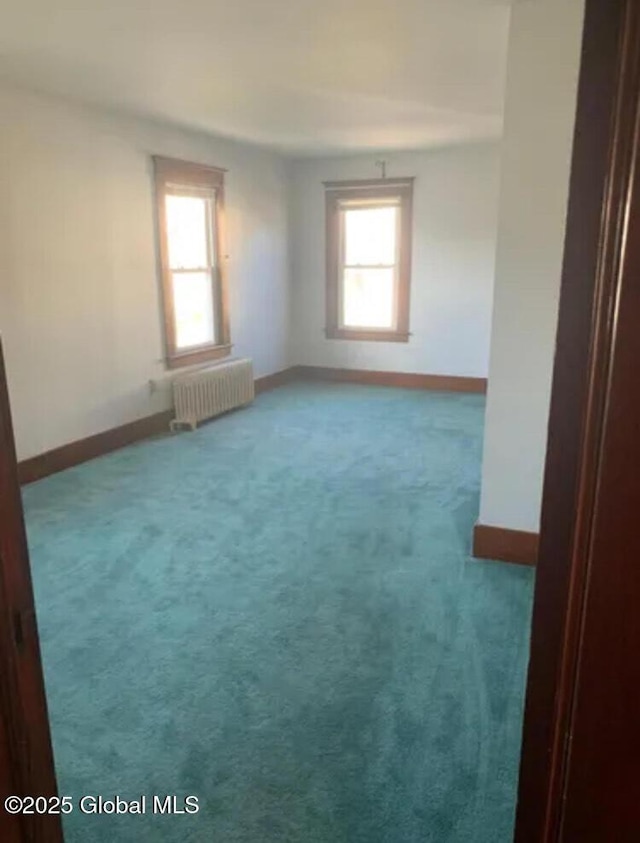 carpeted spare room with radiator and baseboards