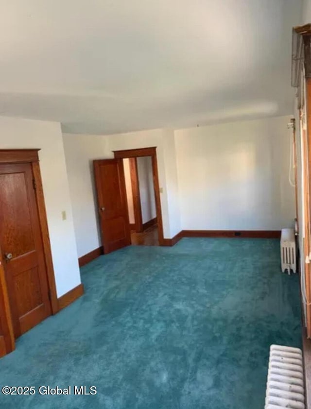 spare room with carpet, baseboards, and radiator