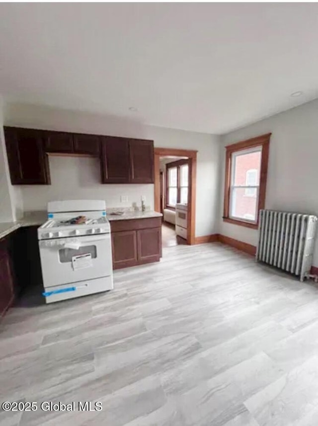 kitchen with gas range gas stove, light countertops, baseboards, and radiator