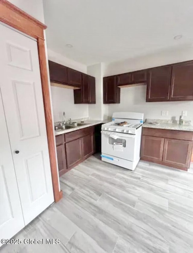 kitchen with white gas stove, light countertops, and a sink