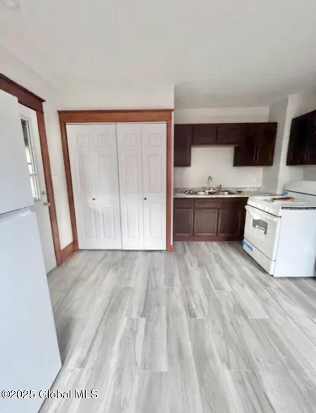 kitchen featuring a sink, light wood-style floors, white appliances, light countertops, and dark brown cabinets