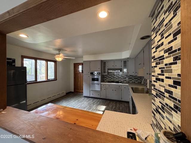 kitchen with under cabinet range hood, ceiling fan, black appliances, gray cabinetry, and a baseboard radiator