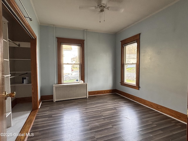 spare room with wood finished floors, a ceiling fan, and baseboards