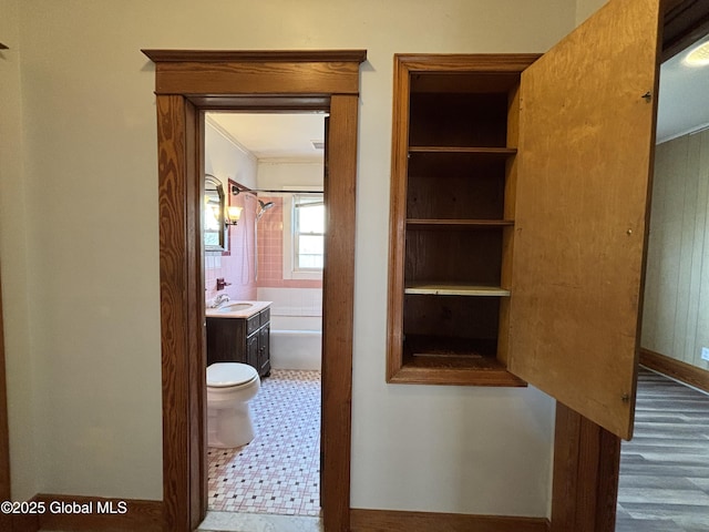 corridor featuring wood finished floors, crown molding, and a sink