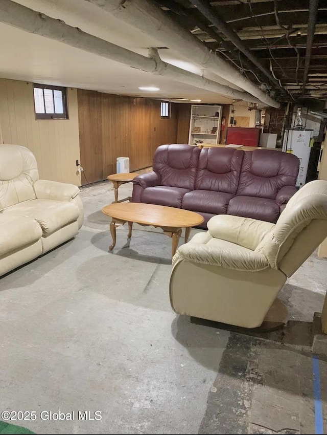 living room with gas water heater, concrete flooring, and wood walls