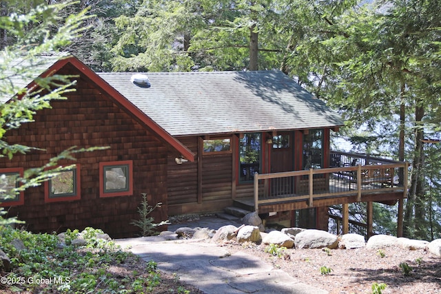 view of front of home featuring roof with shingles and a deck