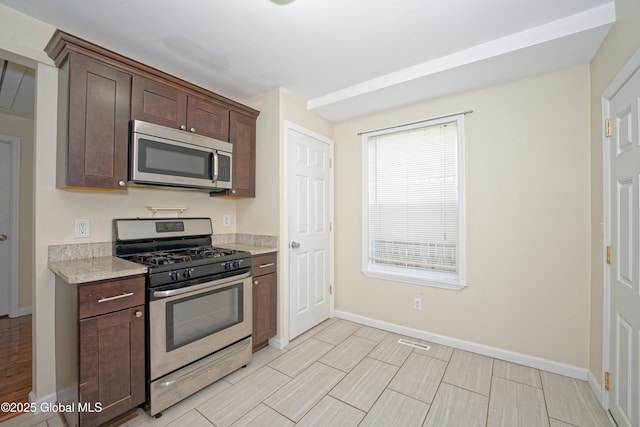 kitchen featuring wood tiled floor, dark brown cabinetry, stainless steel appliances, baseboards, and visible vents