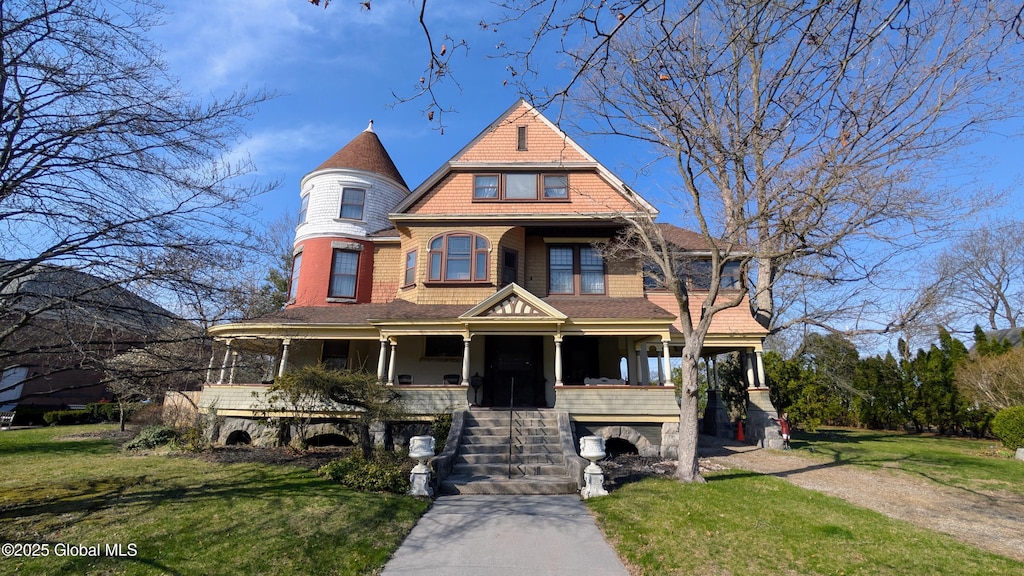 victorian home with a porch, a front lawn, stairs, concrete driveway, and an attached garage