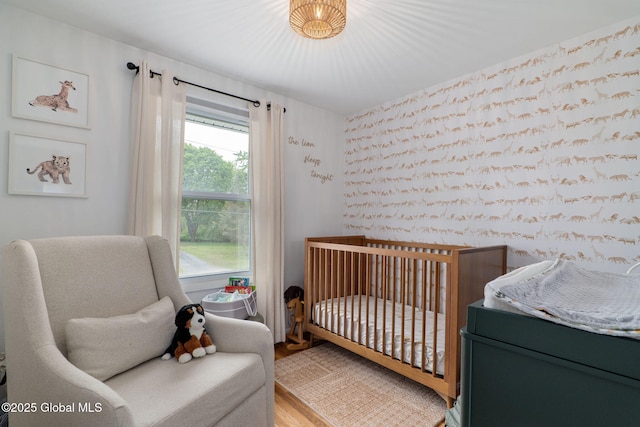 21 St Charles Pl, Saratoga Springs, NY 12866 - bedroom featuring a crib, wood finished floors, and wallpapered walls