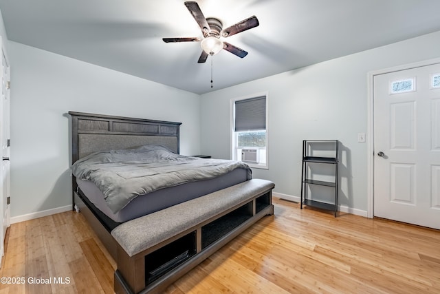 bedroom featuring cooling unit, light wood-style flooring, baseboards, and ceiling fan