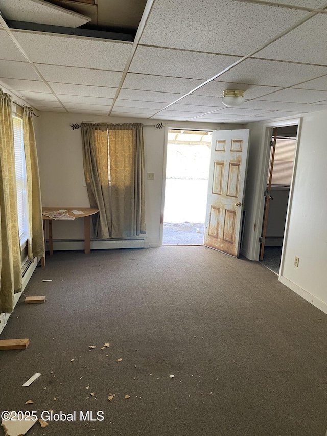 carpeted empty room with baseboards, a baseboard heating unit, and a drop ceiling