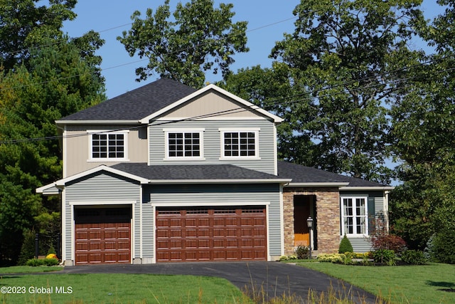 view of front facade with a garage, a shingled roof, driveway, and a front yard