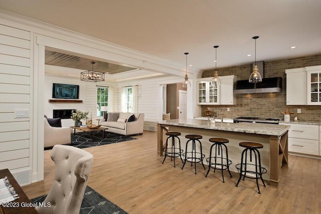 kitchen featuring a chandelier, light wood-style floors, white cabinets, a kitchen bar, and open floor plan