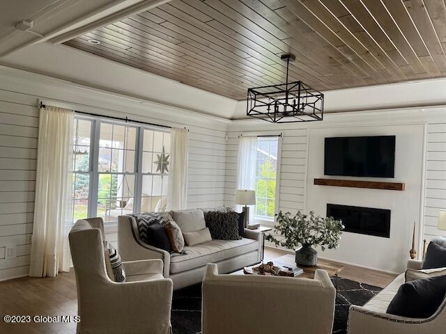 living area featuring wood finished floors, wood ceiling, wood walls, a fireplace, and a notable chandelier