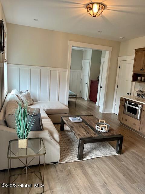 living area with wainscoting, light wood finished floors, and a decorative wall