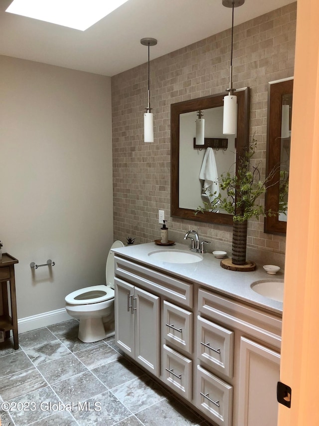 full bathroom with a sink, double vanity, baseboards, toilet, and backsplash