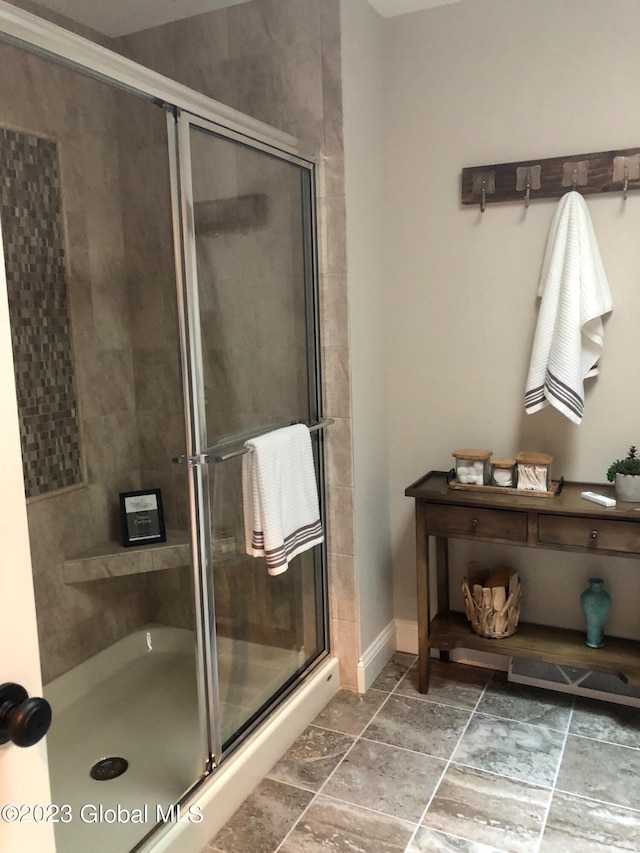 full bath featuring a shower stall and baseboards