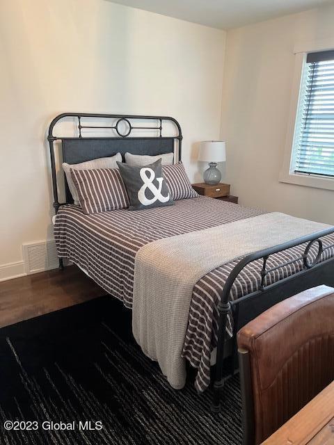 bedroom with visible vents, wood finished floors, and baseboards