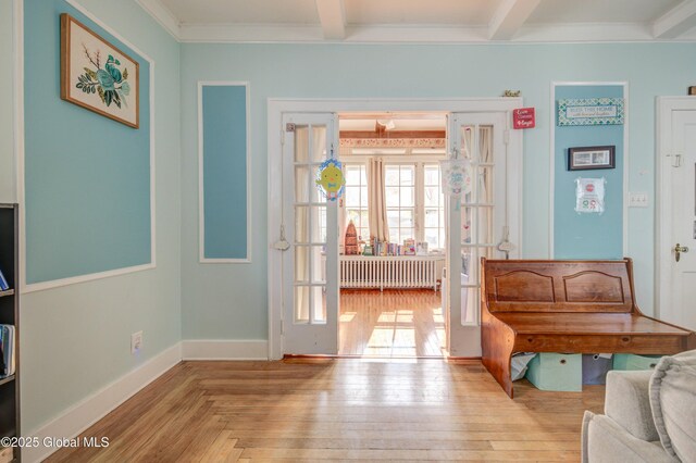 foyer featuring radiator heating unit, ornamental molding, beamed ceiling, and baseboards