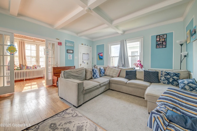 living area featuring wood-type flooring, coffered ceiling, radiator heating unit, and beam ceiling