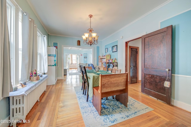 dining area featuring a chandelier, crown molding, baseboards, and light wood-style floors